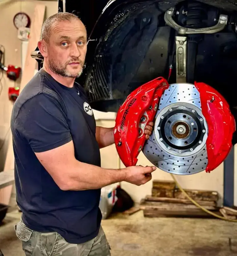 Lead mechanic with a big brake kit caliper and drilled rotor
